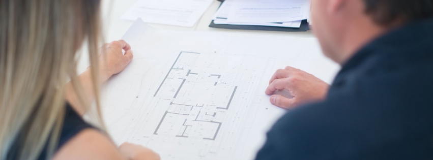 Two people reviewing a floor plan and blueprint documents during IT planning for business expansion