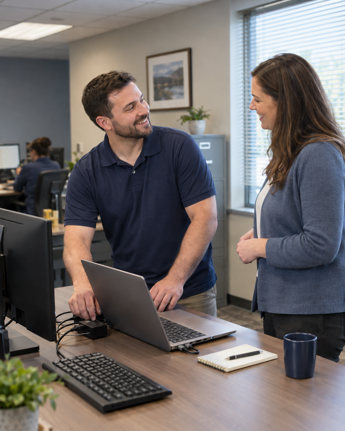 Two colleagues talking beside a laptop in an office.